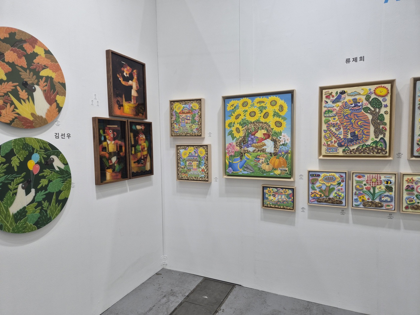 원형 부조 작품과 해바라기 그림, 색색의 부조 회화가 걸린 부스 코너