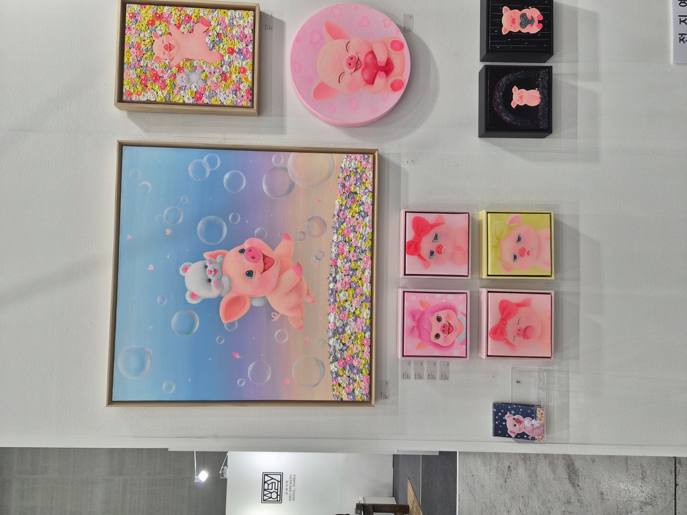 큰 돼지 그림 한 점과 그 아래 정사각형 소품 그림 네 점이 나란히 걸린 벽