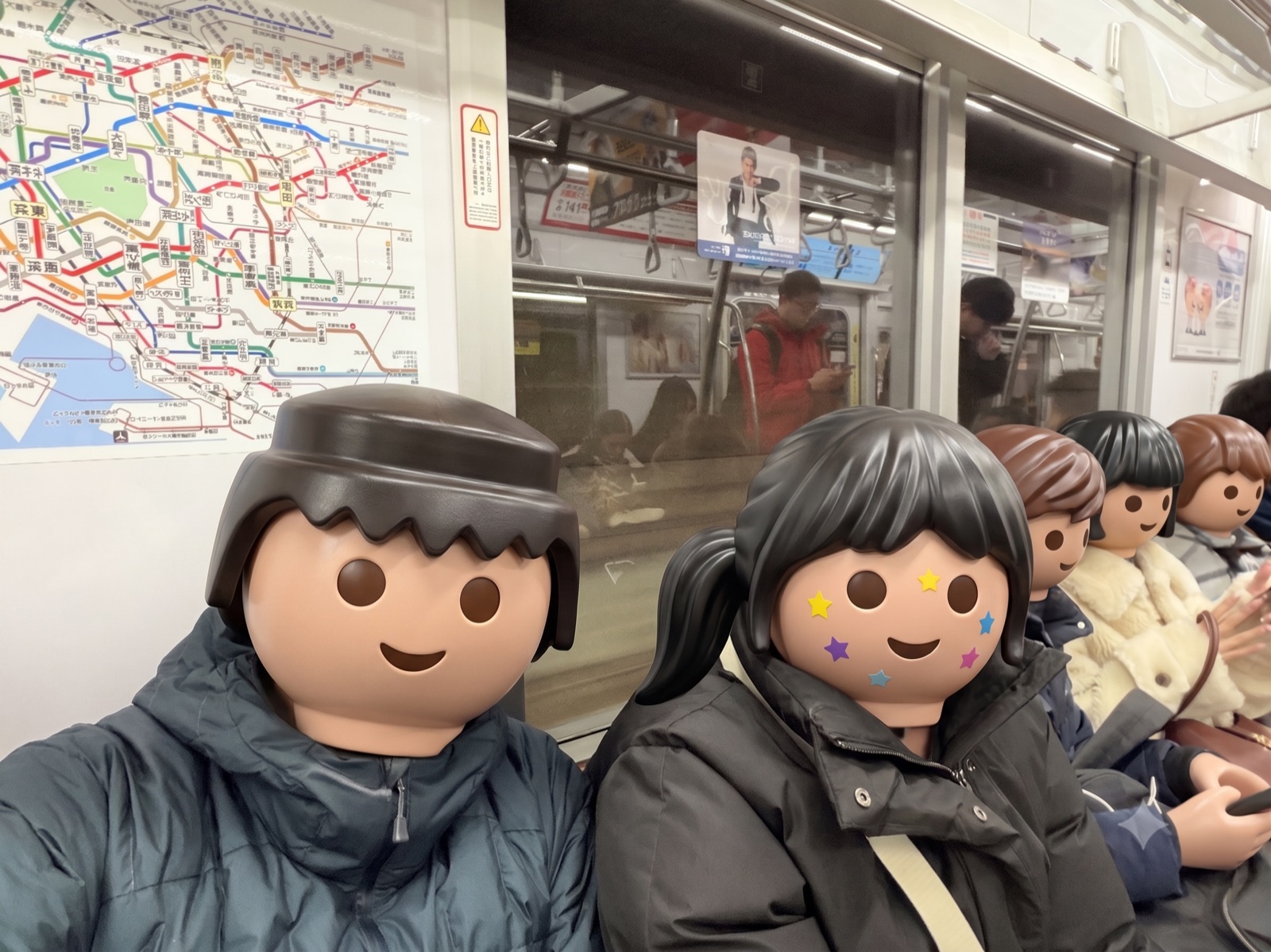 도쿄 전철 안 노선도 옆에 나란히 앉은 가족